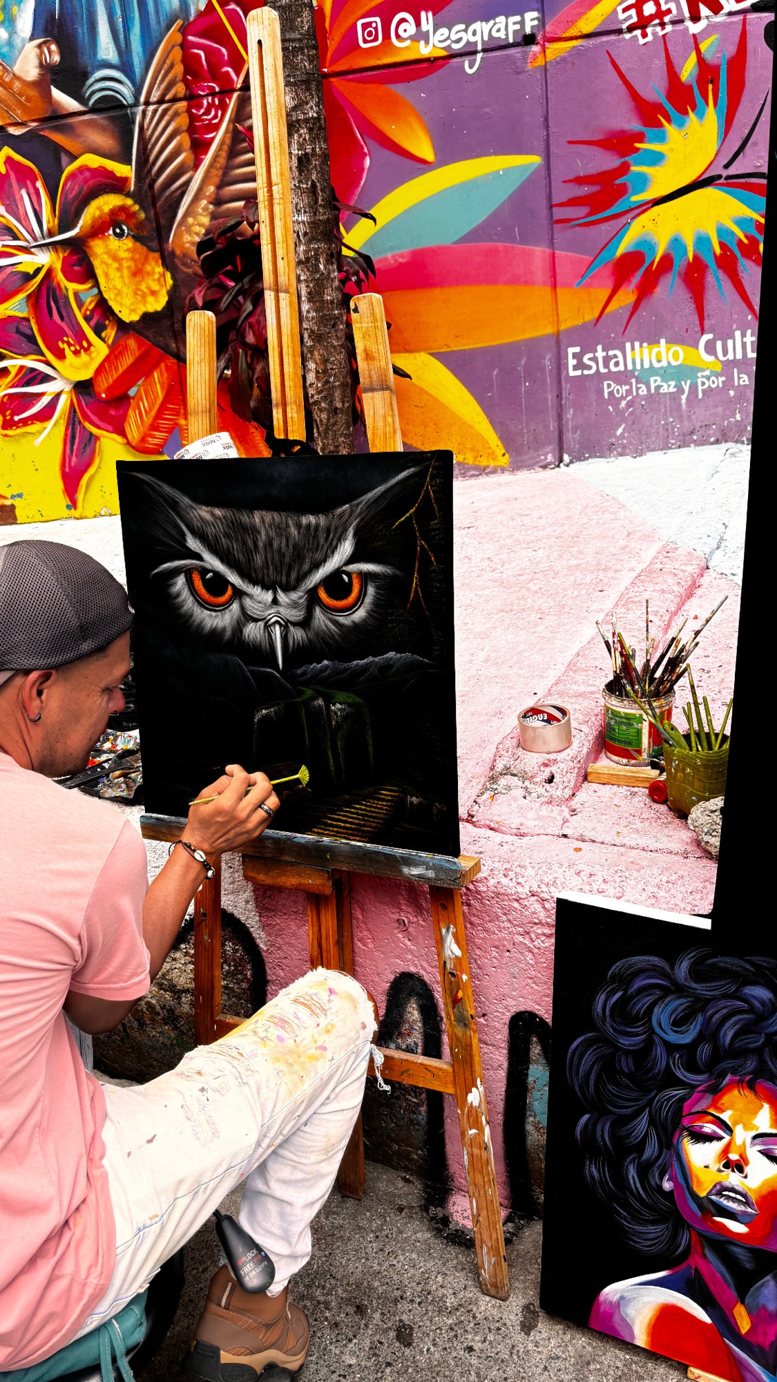 Artista pintando un búho sobre lienzo en una calle de la Comuna 13