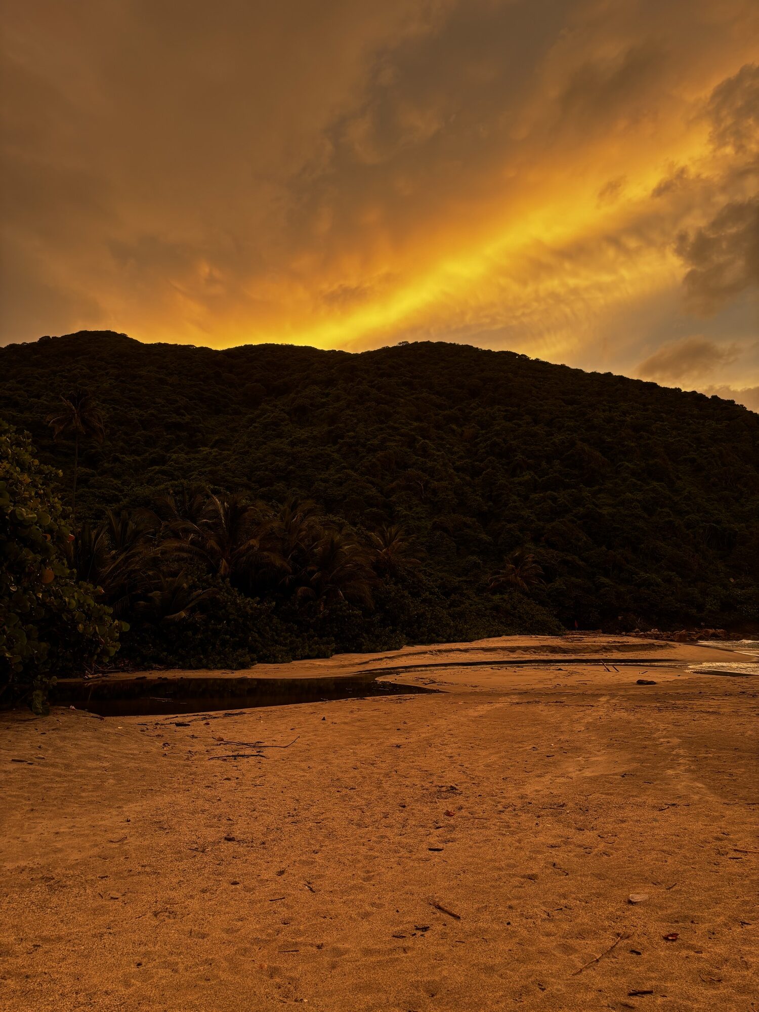 Atardecer anaranjado sobre la montaña de Playa Brava en el Parque Tayrona