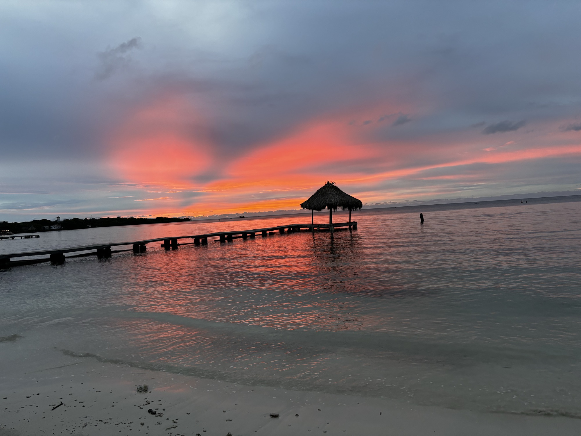 Cielo rosa al atardecer reflejado en el mar junto al muelle de Isla Grande, Islas del Rosario
