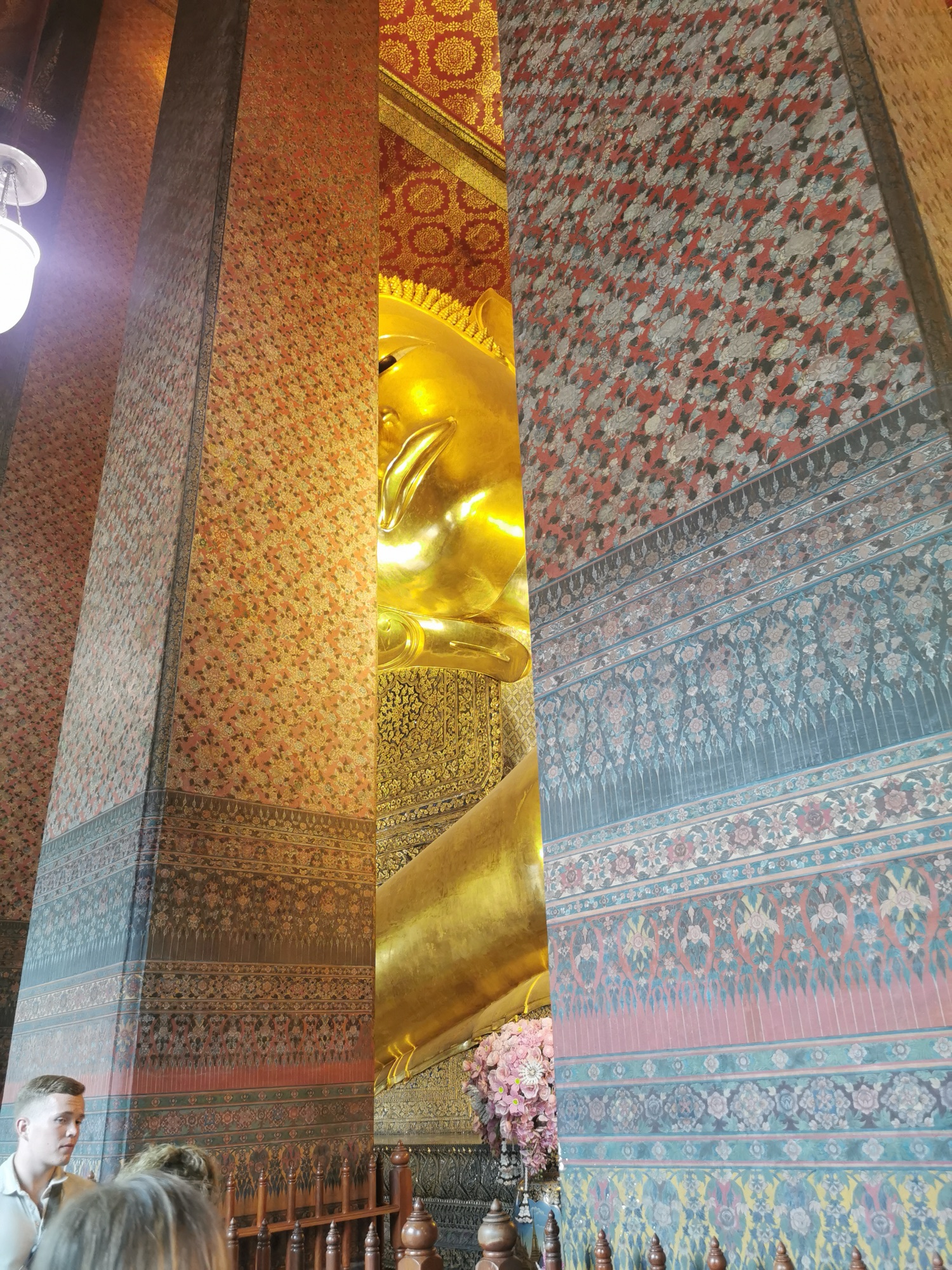 Detalle del Buda reclinado dorado del Wat Pho entre columnas decoradas