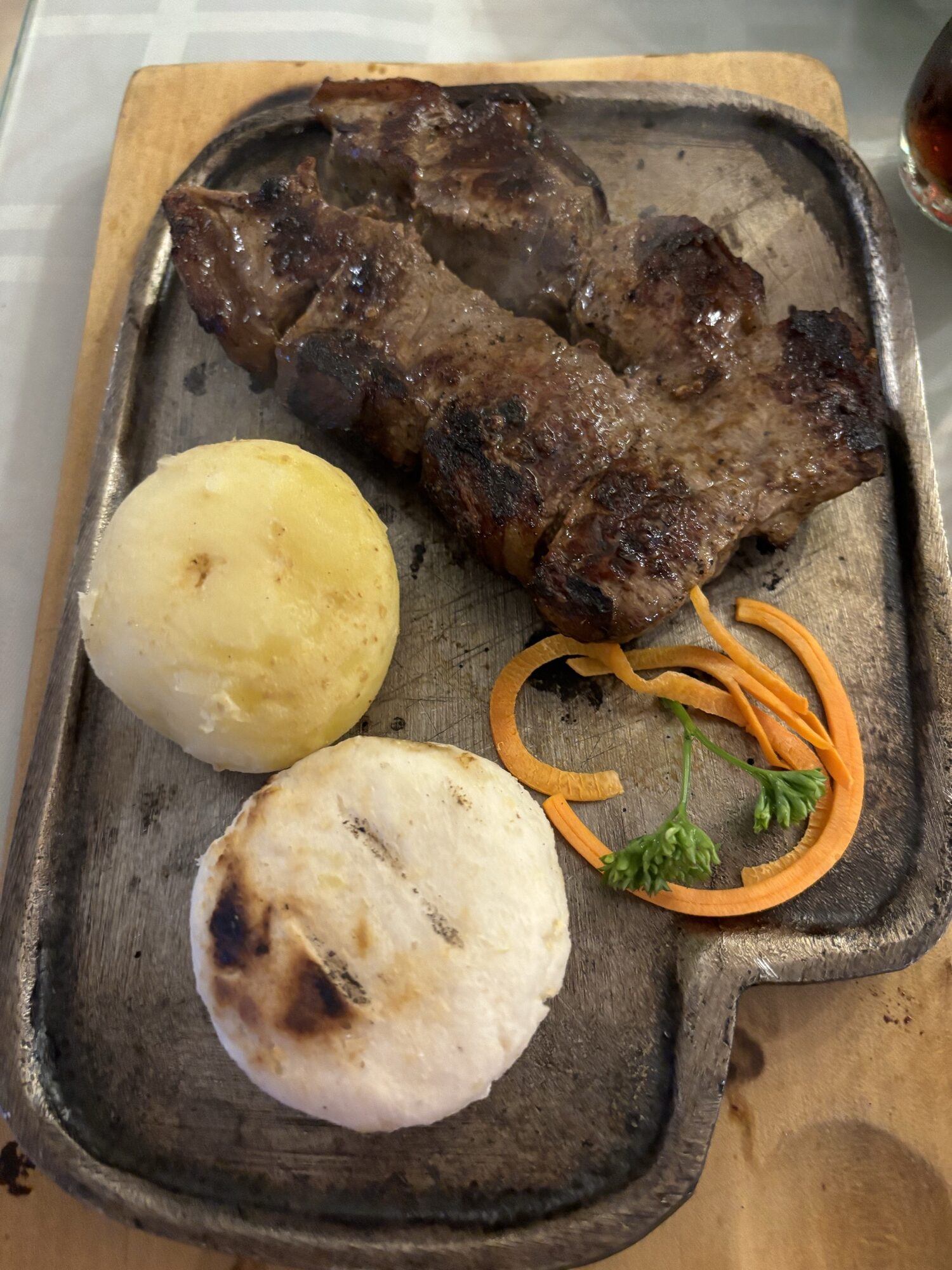 Carne asada con arepas y zanahoria servida en plancha de hierro en Salento