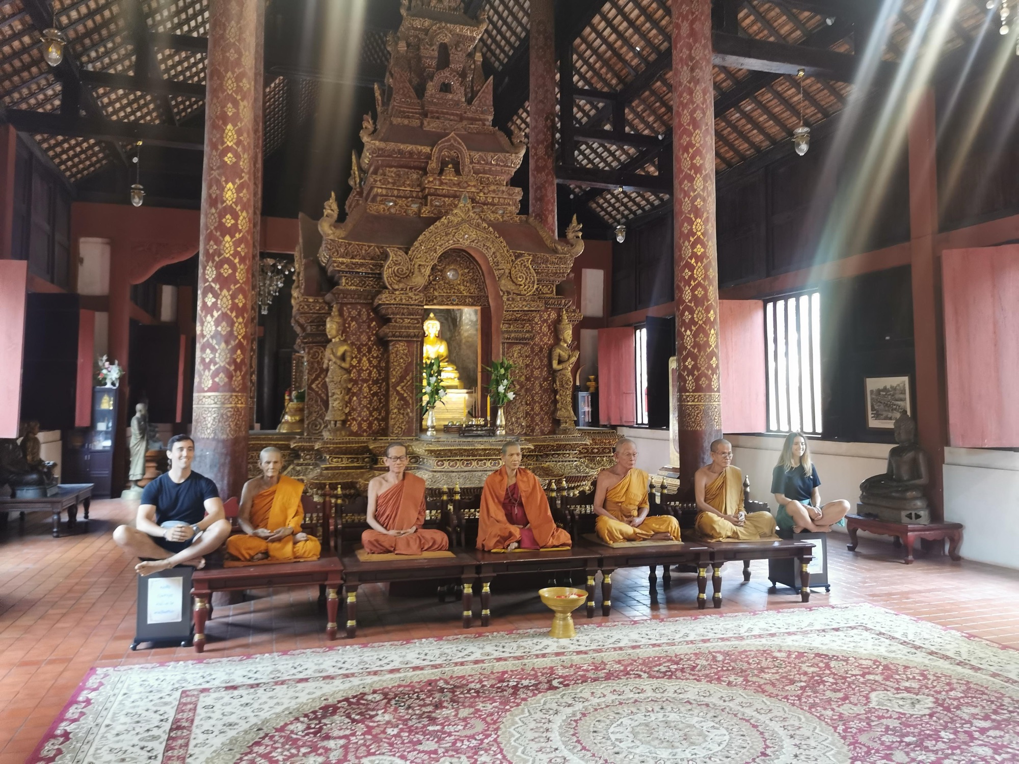 Figuras de monjes sentados en fila en la sala de un templo de Chiang Mai