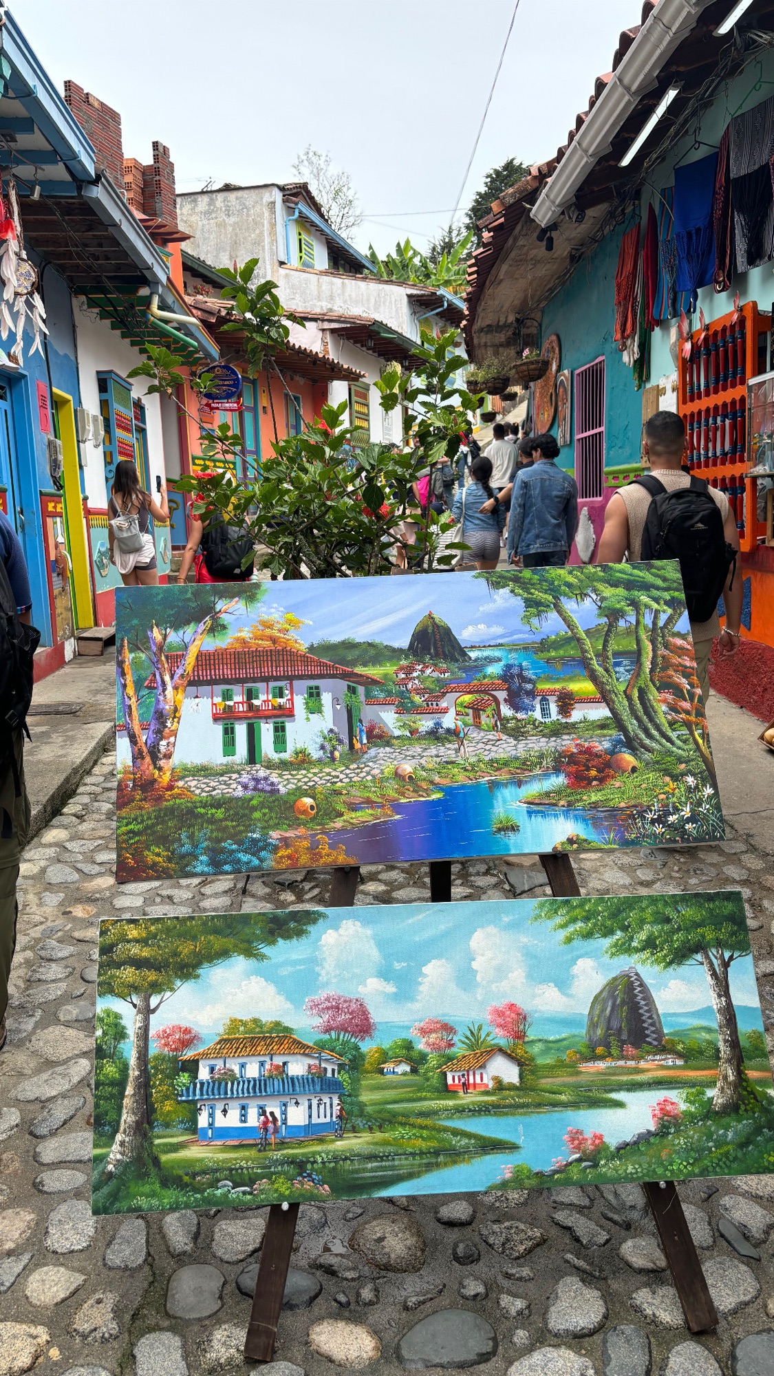 Cuadros de Guatapé y la Piedra del Peñol en venta en la Calle de los Recuerdos, entre casas de zócalos de colores