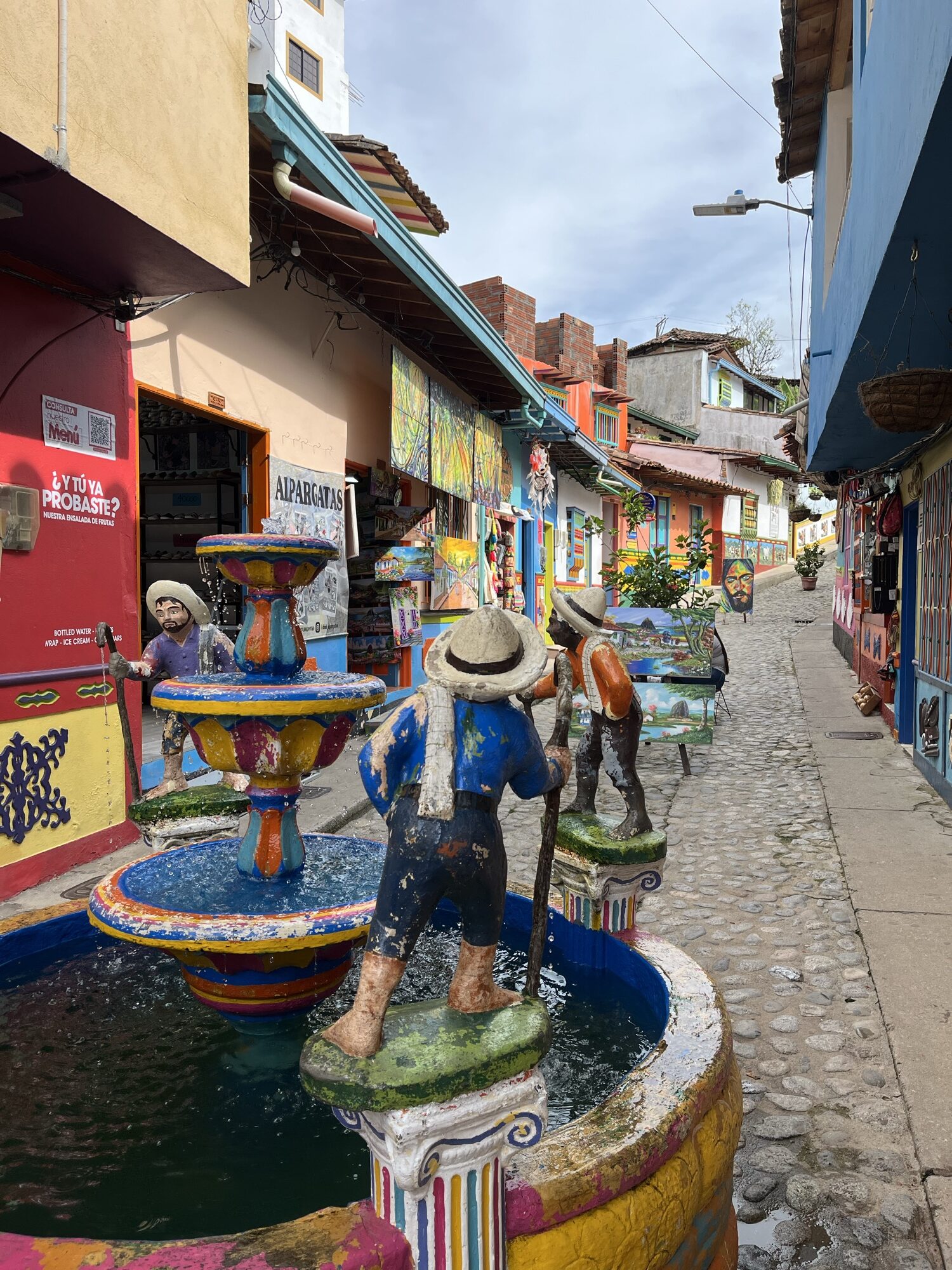 Fuente de colores con figuras paisas en la Calle 30 de Guatapé, rodeada de fachadas con zócalos