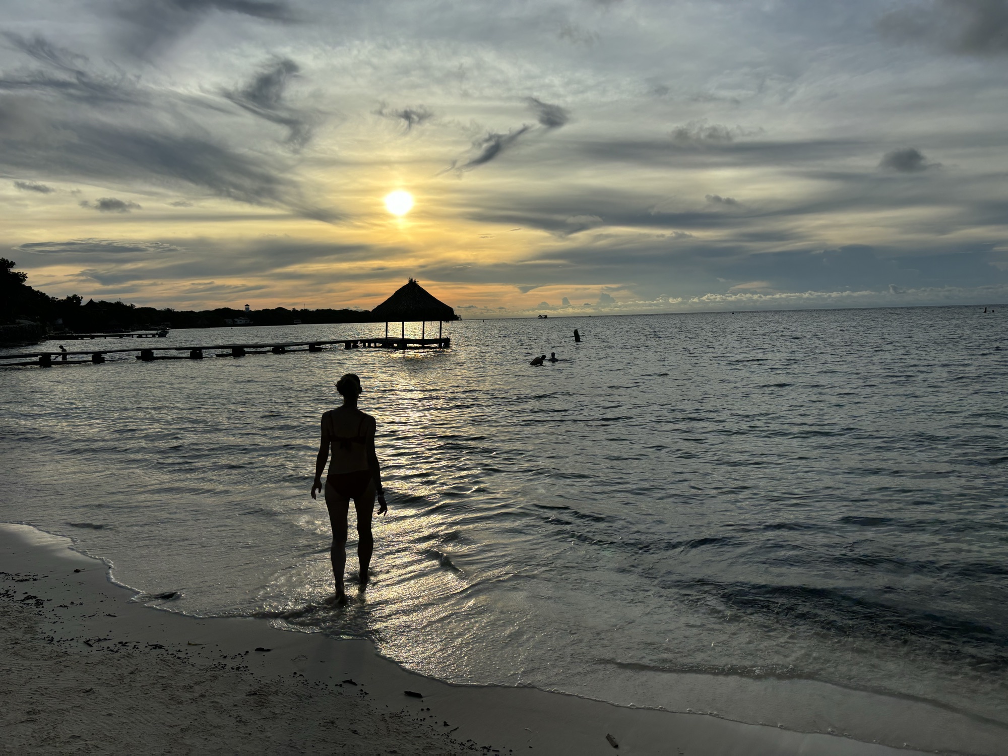 Laura en la orilla al atardecer frente al muelle de La Cocotera, en Isla Grande