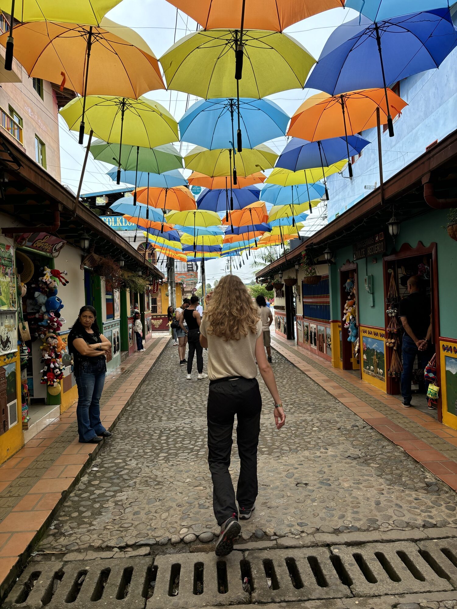 Laura caminando bajo la calle de los paraguas de colores junto a la plaza del Zócalo de Guatapé