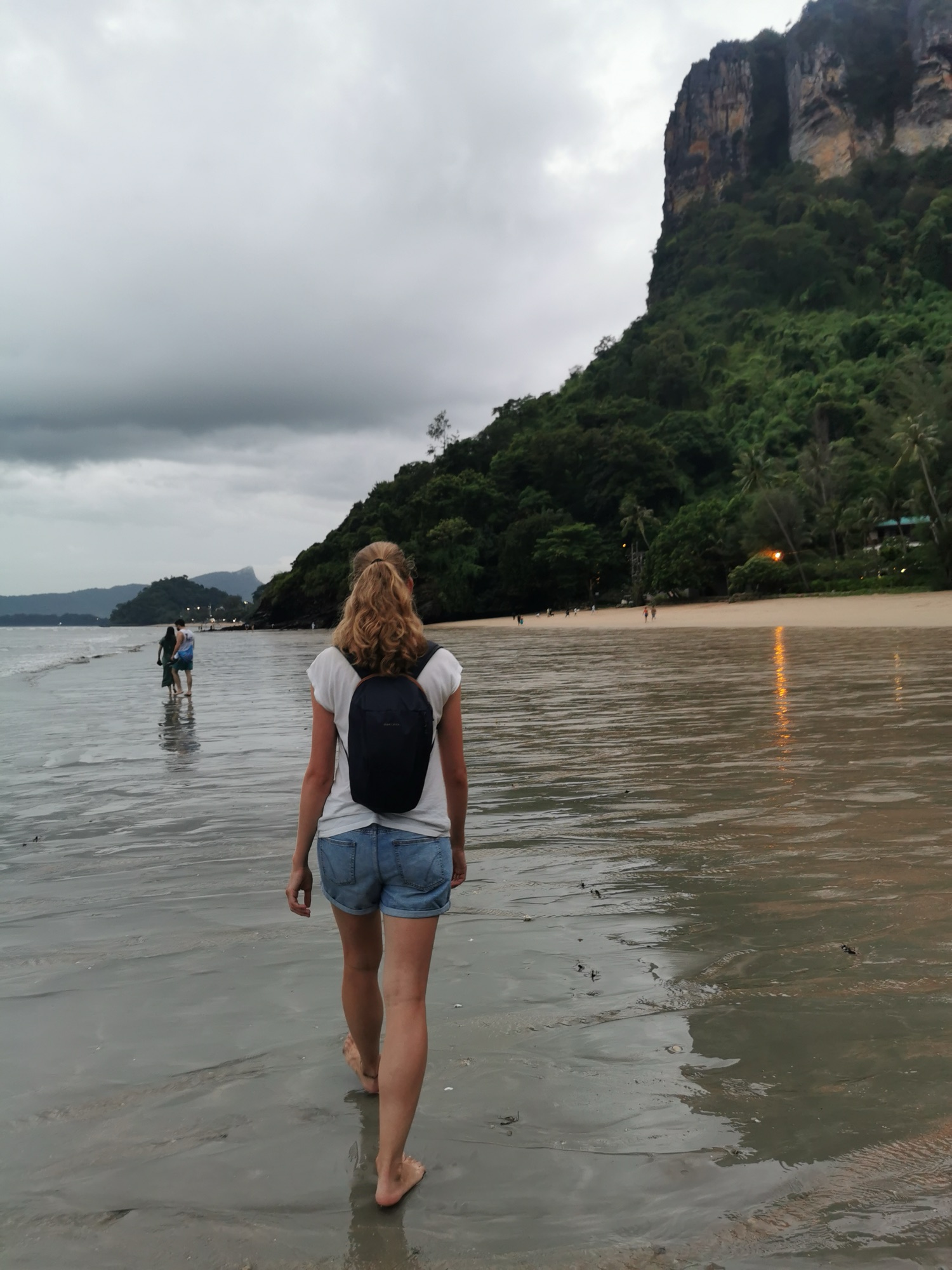 Laura de espaldas caminando por la orilla bajo los acantilados de Ao Nang