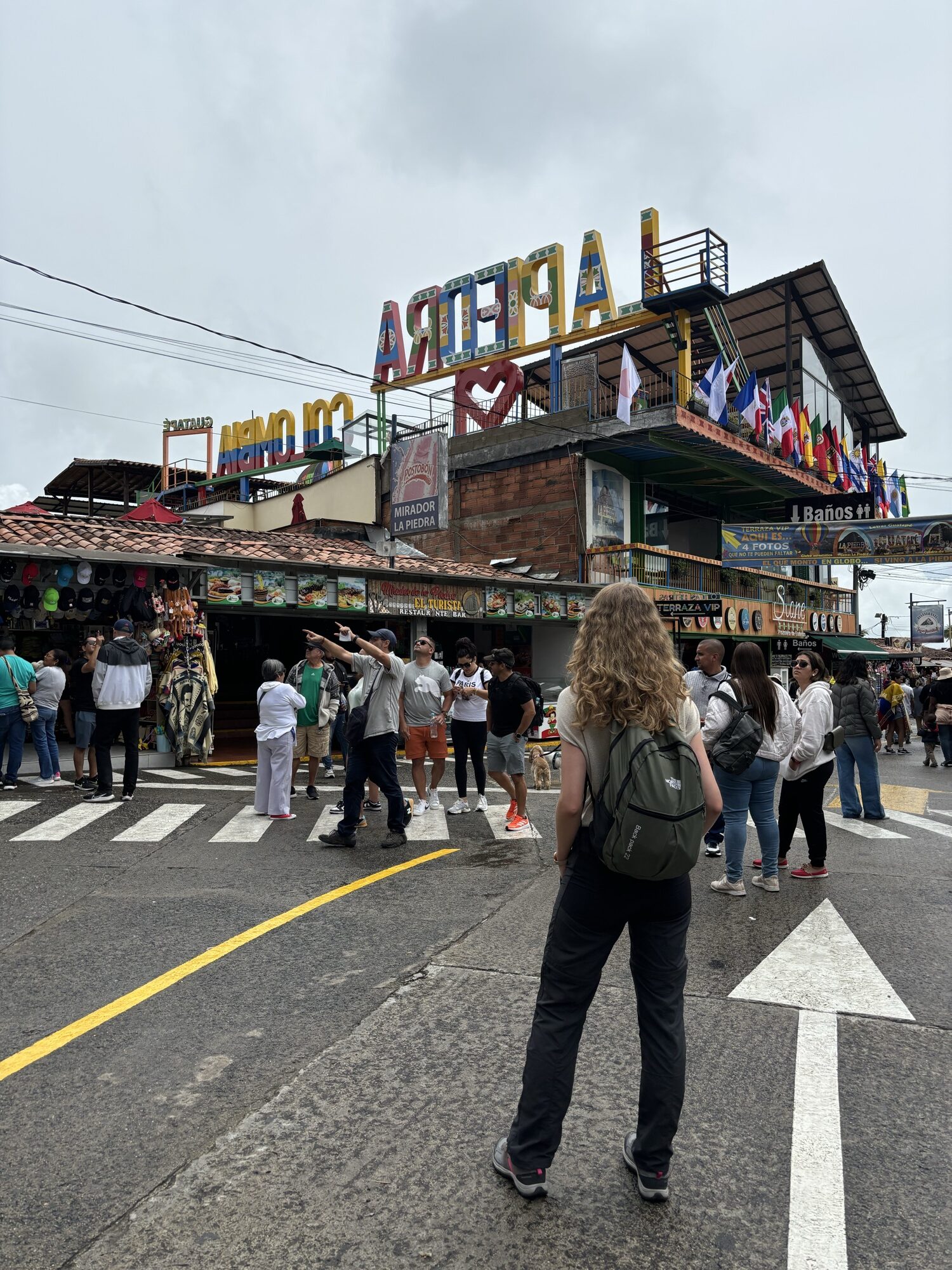 Laura frente al cartel de La Piedra y los restaurantes a los pies de la Piedra del Peñol