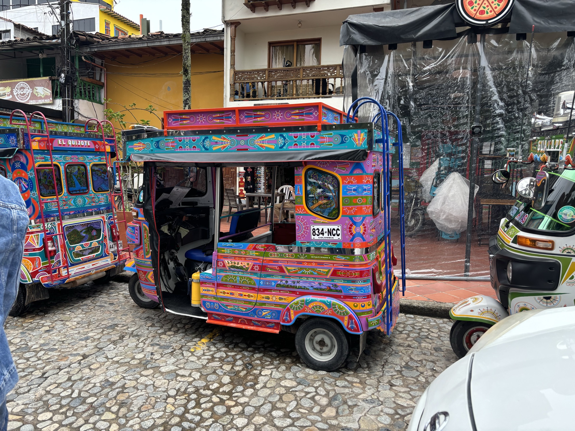 Mototaxis decorados con colores vivos aparcados en una calle empedrada de Guatapé