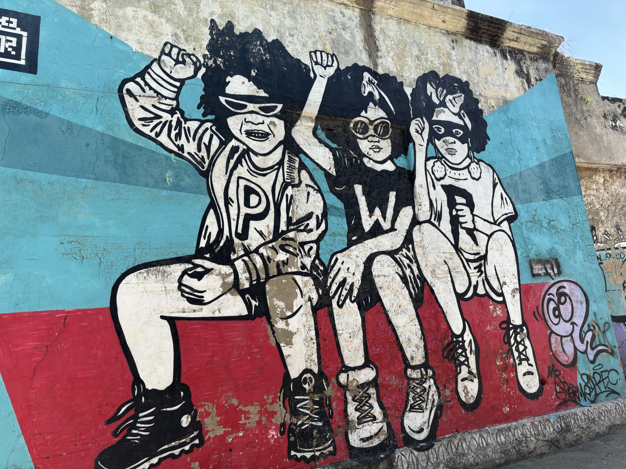 Mural de tres niños en blanco y negro sobre fondo azul en las calles de Getsemaní, Cartagena