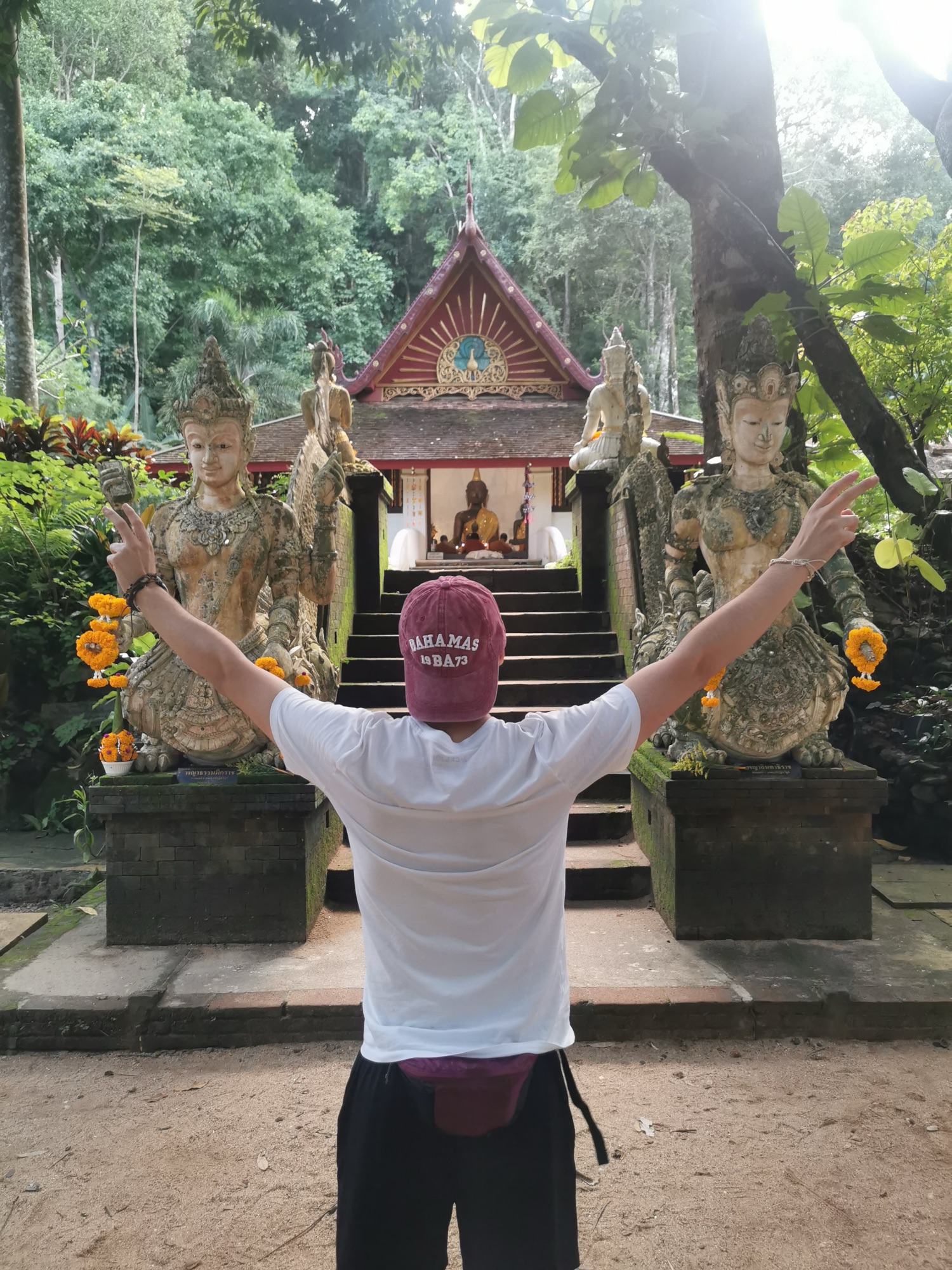 Pablo con los brazos abiertos frente a un pequeño templo en la selva del Wat Pha Lat