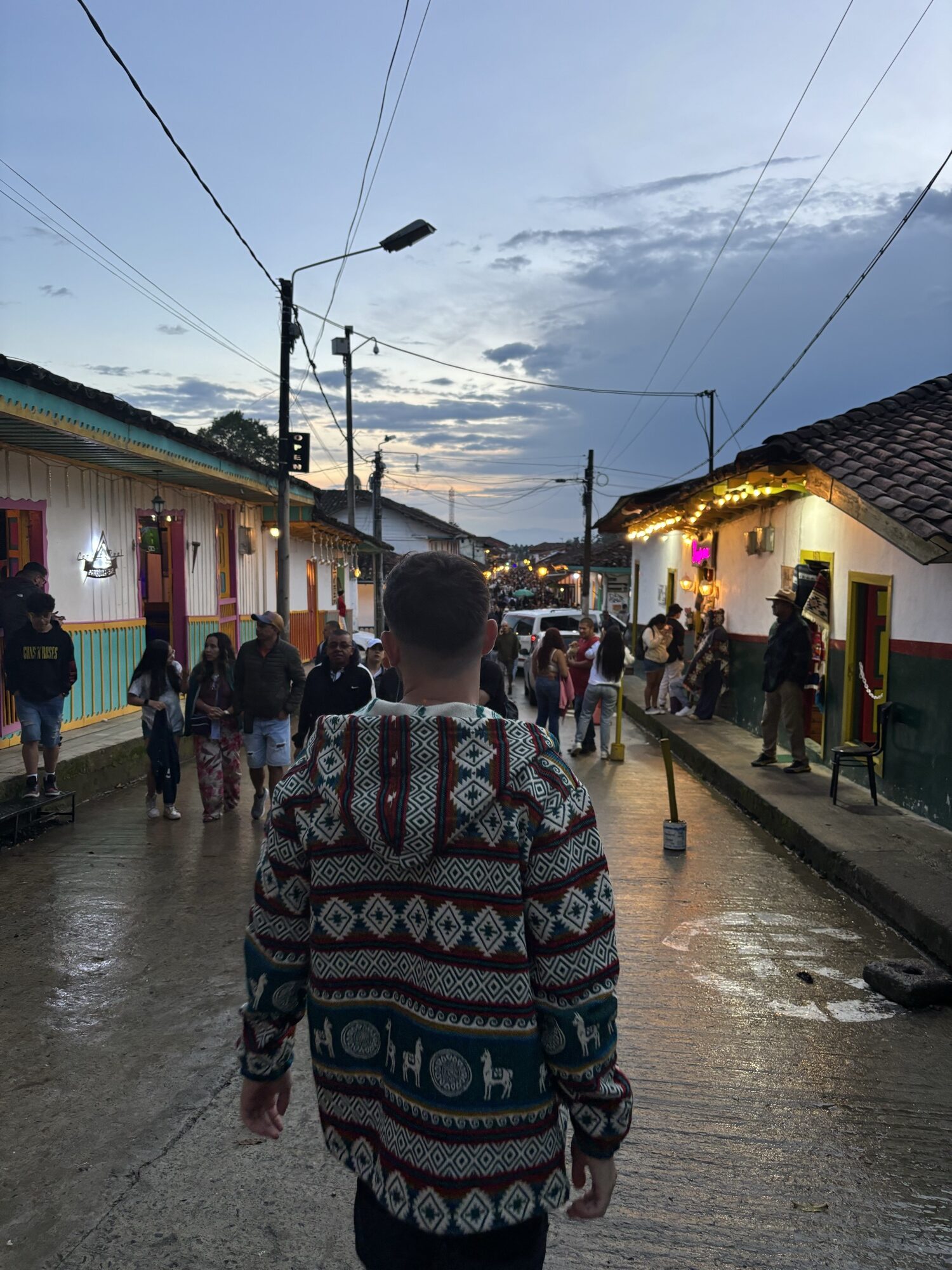 Pablo paseando por una calle de casas de colores en Salento al atardecer