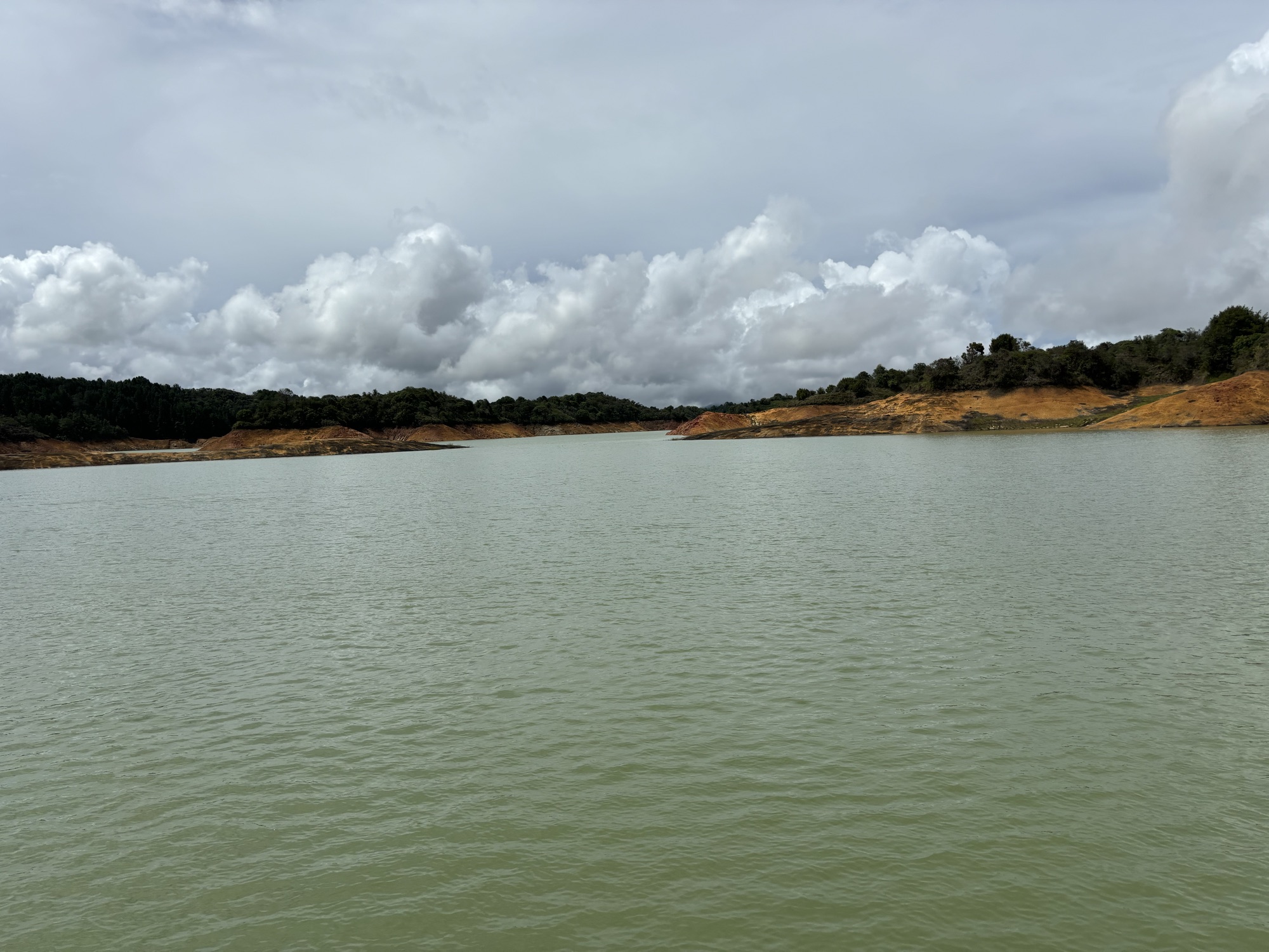 Aguas tranquilas del embalse de Guatapé bajo un cielo nublado durante el paseo en barco