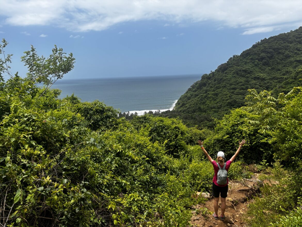 Laura con los brazos en alto en el camino a Playa Brava, con el mar Caribe al fondo