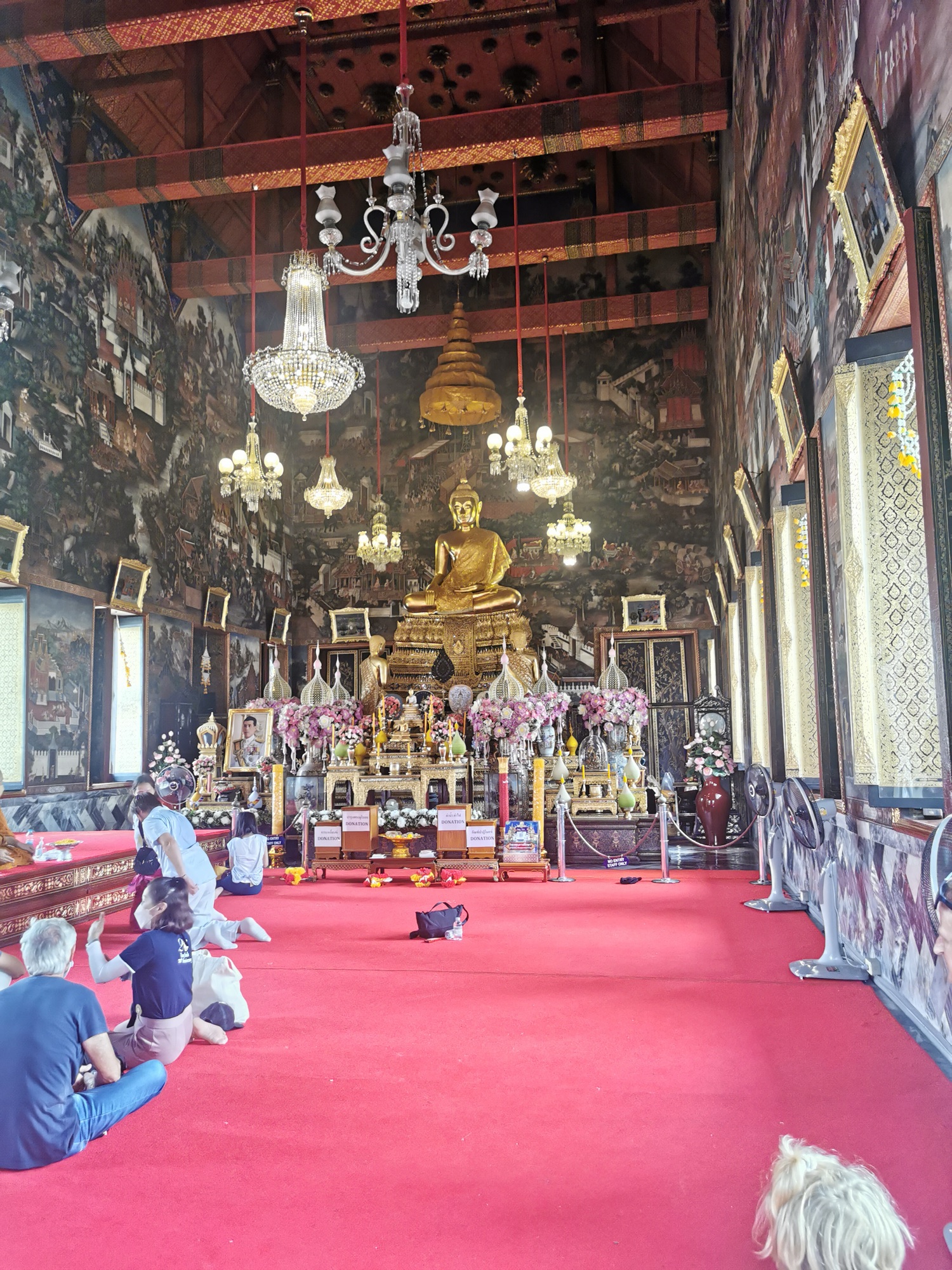 Interior de la sala de ordenación del Wat Arun con su Buda dorado y lámparas de araña